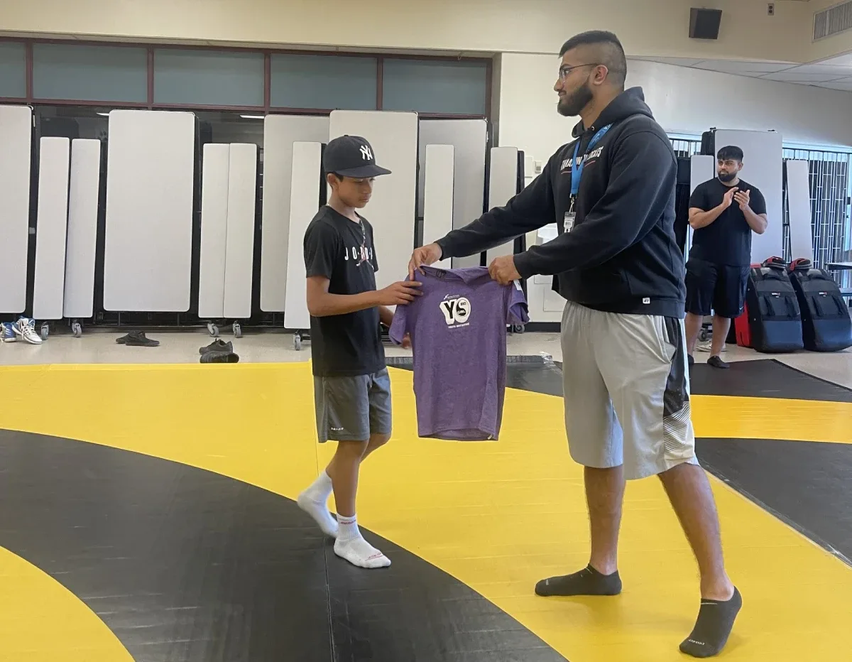 A YBYG mentor presenting a program shirt to a young participant